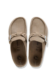 A pair of taupe suede moccasin-style shoes with bow details and silver buckle straps, shown from a top-down view on a white background.