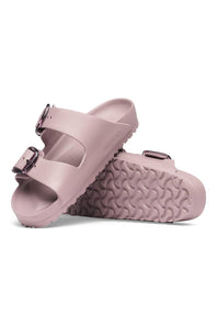 A pair of dusty pink double-strap slide sandals with textured wavy soles and dark metal buckles, shown on a clean white background.