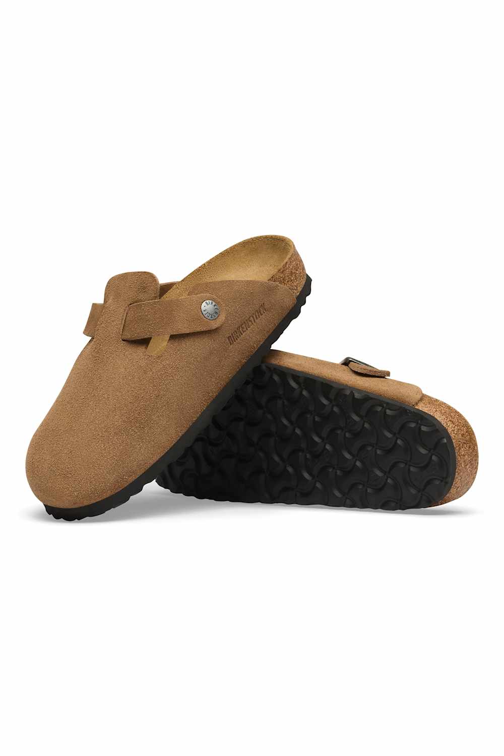 A pair of tan suede clogs with black rubber soles, one standing upright and the other lying on its side to show the tread, set against a plain white background.