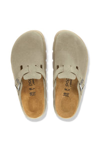 A pair of beige suede clogs shown from a top-down view on a white background. The shoes feature a wide strap with a small silver buckle and a tan insole with the brand name 'paco' visible.