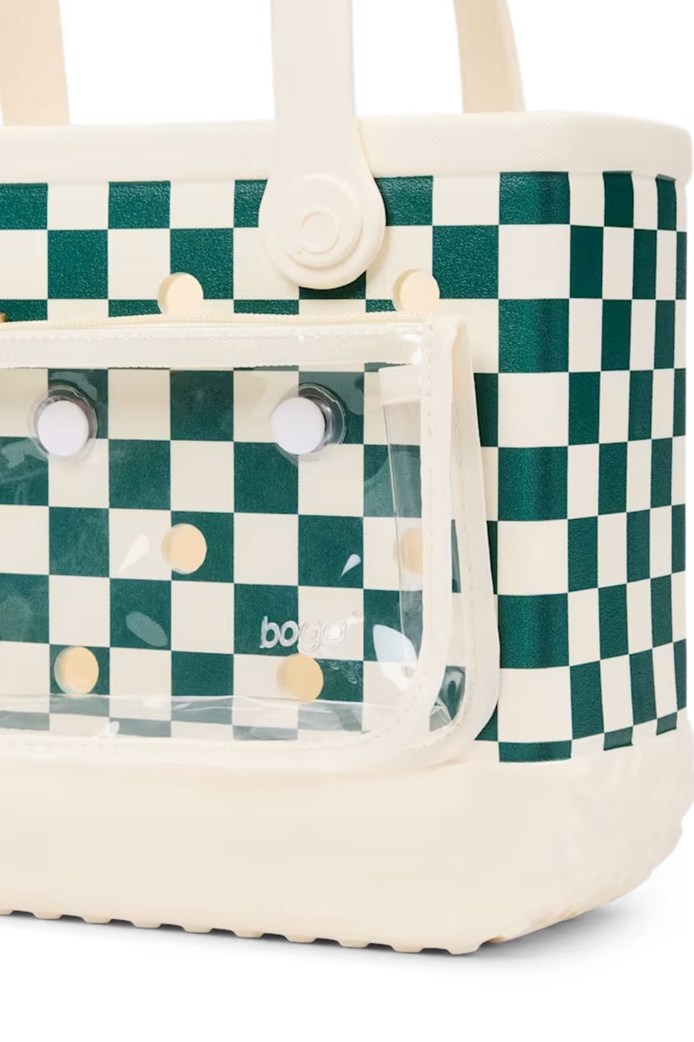 A close-up of a tote bag featuring a green and cream checkerboard pattern, a clear front zip pocket with cream-colored snap buttons, and cream handles.