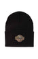 A black knit beanie hat featuring a circular brown and black Carhartt patch on the front cuff.