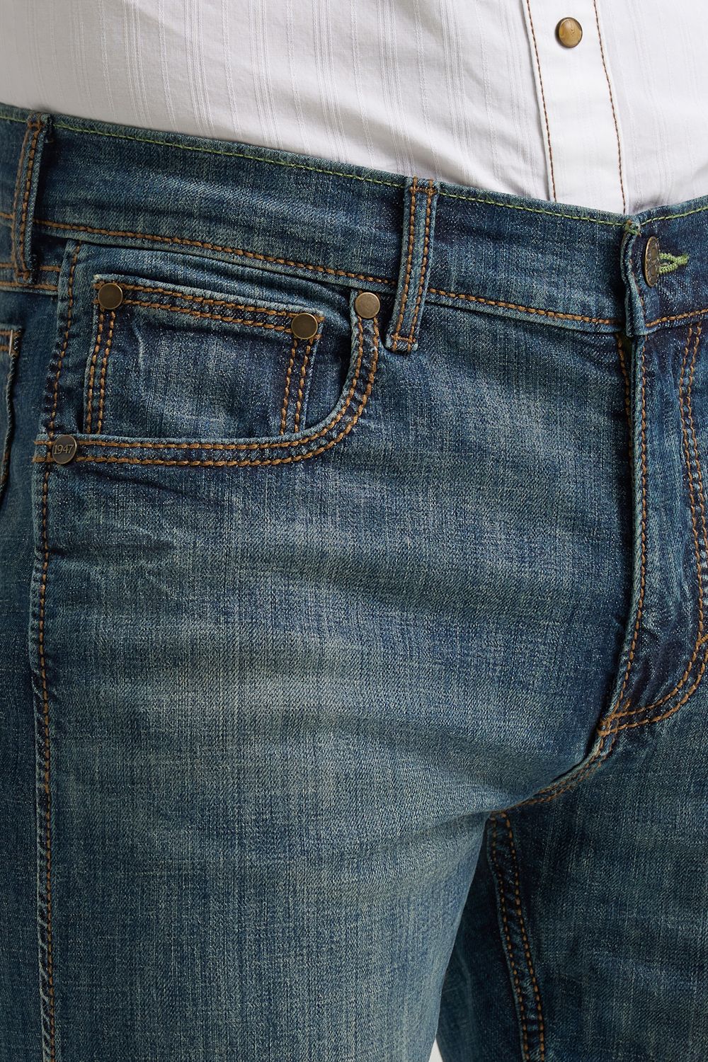 Close-up of a person wearing blue denim jeans with a white button-up shirt visible at the waistband.