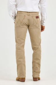 A person shown from the back wearing beige denim jeans with a white long-sleeve shirt and brown shoes, photographed against a plain light background.