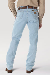 Rear view of a person wearing light-wash blue jeans with a brown belt, tan shirt, and brown shoes against a light gray studio background.