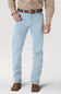 A person wearing light-wash blue jeans with a brown belt, tan button-up shirt, and brown woven shoes, shown from the waist down on a light gray studio background.