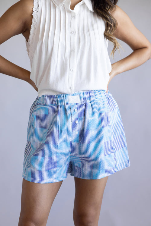 Striped Boxer Shorts for Women in Blue Checkered; Person wearing a white sleeveless top and blue checkered shorts on a plain background