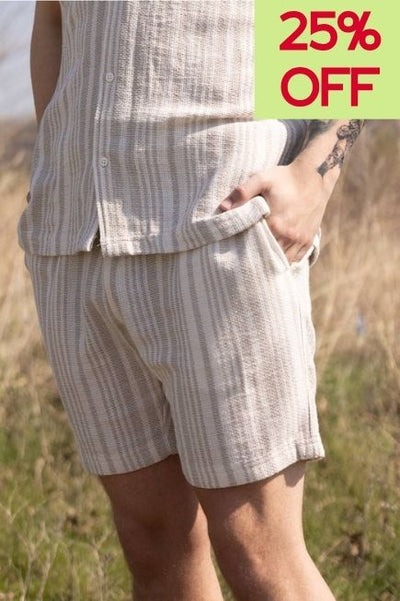 Man wearing a matching shirts shirt and shorts set in a grassy field with a 25% off callout in the upper right corner