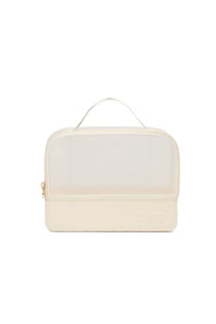 An off-white double-compartment travel organizer bag with a clear top window, a top carry handle, and a small embossed logo on the bottom right.