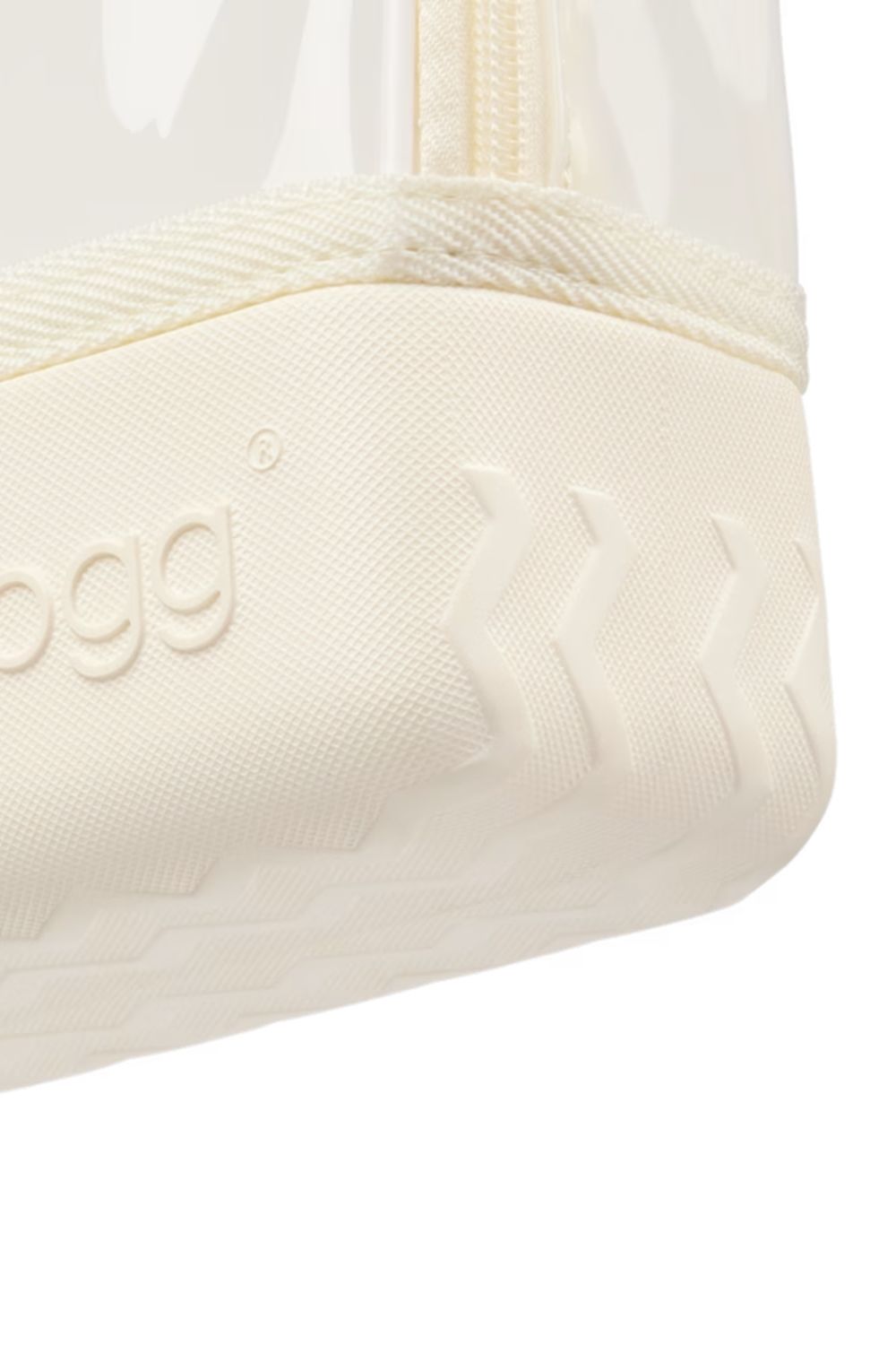 Close-up of a cream-colored shoe sole with embossed branding and tread patterns, showing part of a clear upper and zipper near the top edge.