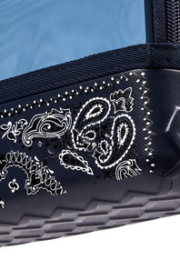 Close-up of a dark navy or black textured fabric accessory with white paisley bandana-style embroidery and dotted trim, against a light blue background.