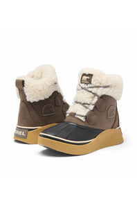 A pair of Merrel mid-calf winter boots in brown and black with thick tan soles and cream shearling lining, shown against a plain white background.