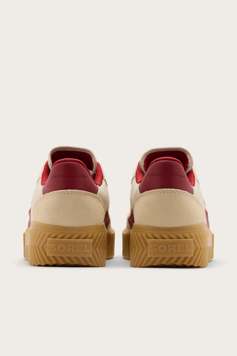 A pair of low-top sneakers shown from the back, featuring cream suede uppers, deep red leather panels on the heel and tongue, and thick textured gum rubber soles with the brand name 'GOREBI' embossed.