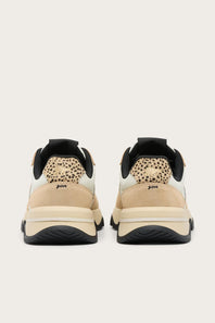 A pair of low-top sneakers shown from the back, featuring beige and cream panels, a black leopard-print heel tab, and chunky black and beige midsoles on a light gray background.