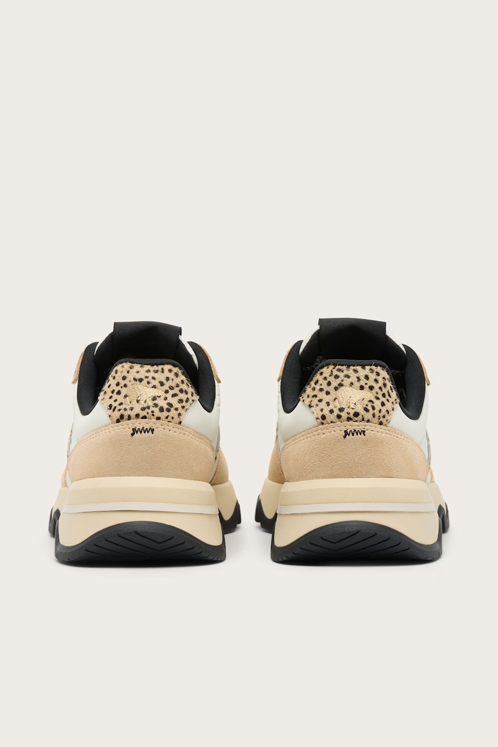 A pair of Juven sneakers shown from the back, featuring beige suede panels, a beige and black leopard print heel tab, black collar lining, and chunky black and beige platform soles.