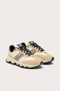 A pair of low-top sneakers in beige, white, and black, featuring a leopard-print side panel and chunky black soles, set against a light beige background.