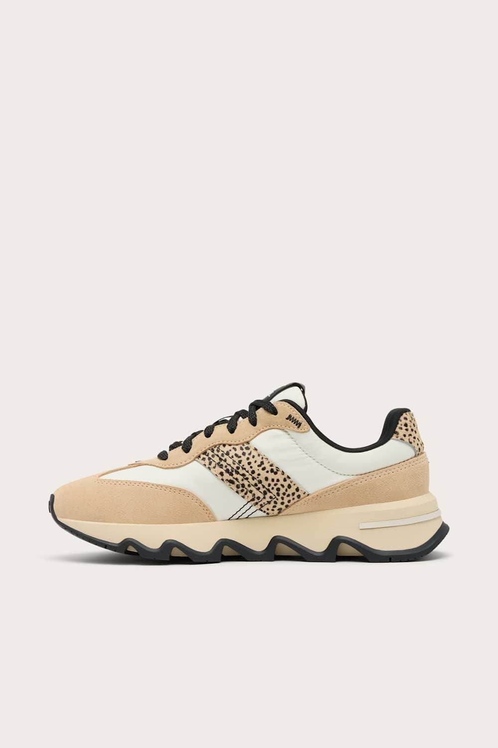 A low-top sneaker in beige and off-white suede and mesh, featuring a leopard-print pattern panel on the side and black laces, shown against a light beige background.