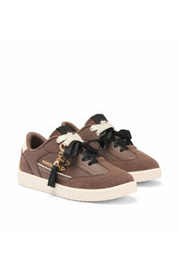 A pair of brown suede sneakers with black ribbon laces, a logo on the side, and a decorative gold key charm with a black tassel attached to the front shoe, set against a plain white background.