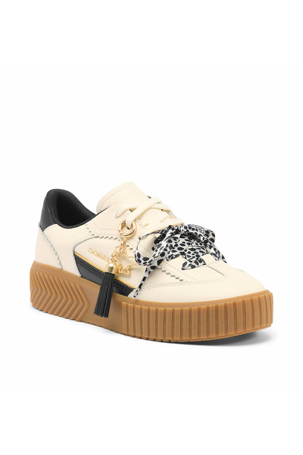A low-top platform sneaker in off-white leather with a thick brown gum sole, a black heel tab, a black-and-white leopard print ribbon tied around the laces, and gold-tone hardware.