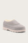 A light gray slip-on clog with a soft cream-colored shearling lining and a thick, textured off-white sole, shown against a solid light gray background.