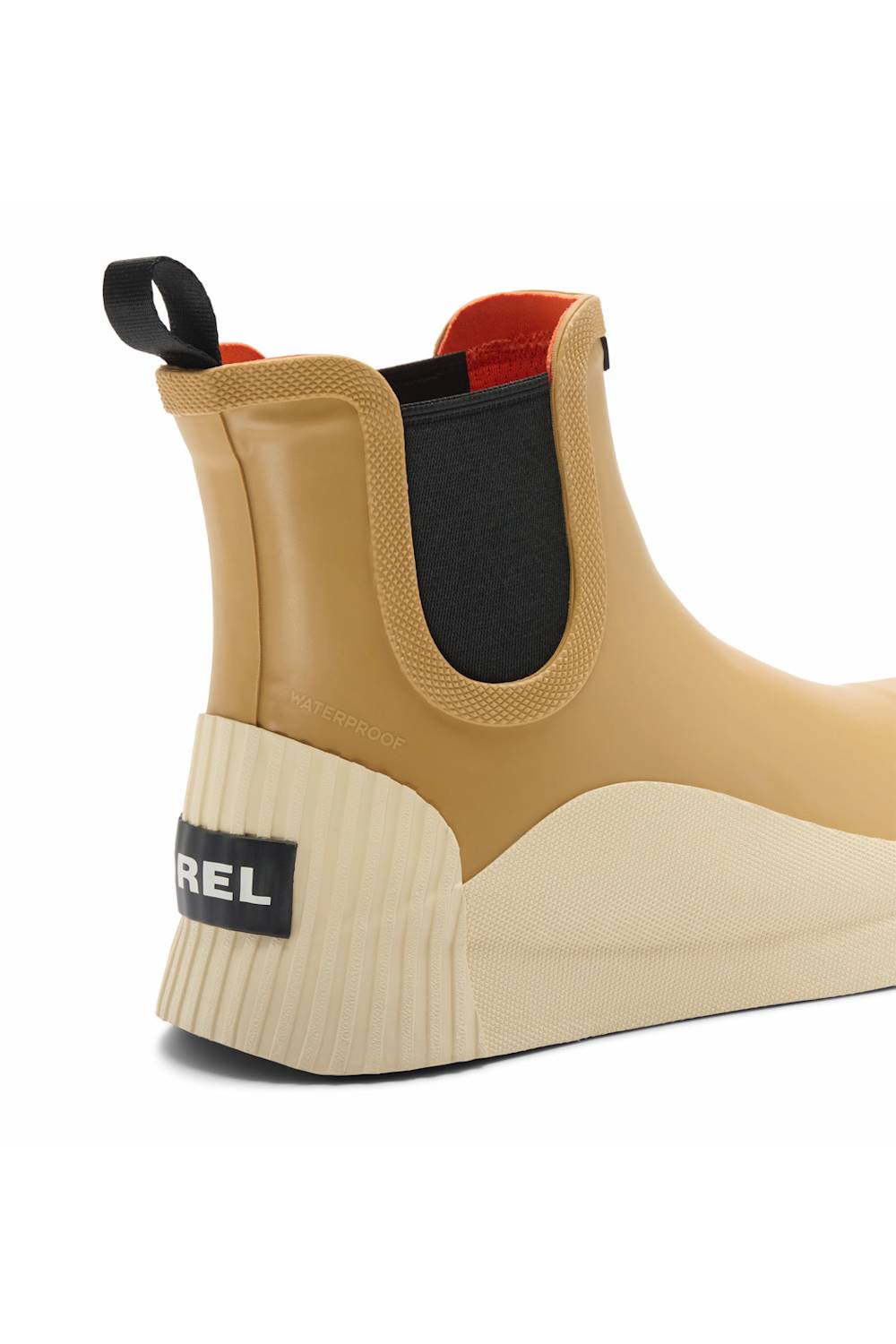 A close-up rear three-quarter view of a  boot in tan and cream, featuring a black elastic side panel, a black heel tab with the brand name, and a red lining visible at the collar.