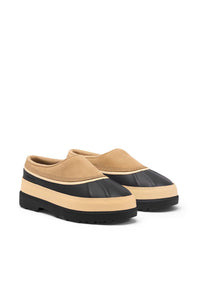 A pair of slip-on platform mule shoes in beige and black, shown from a three-quarters angle on a plain white background.