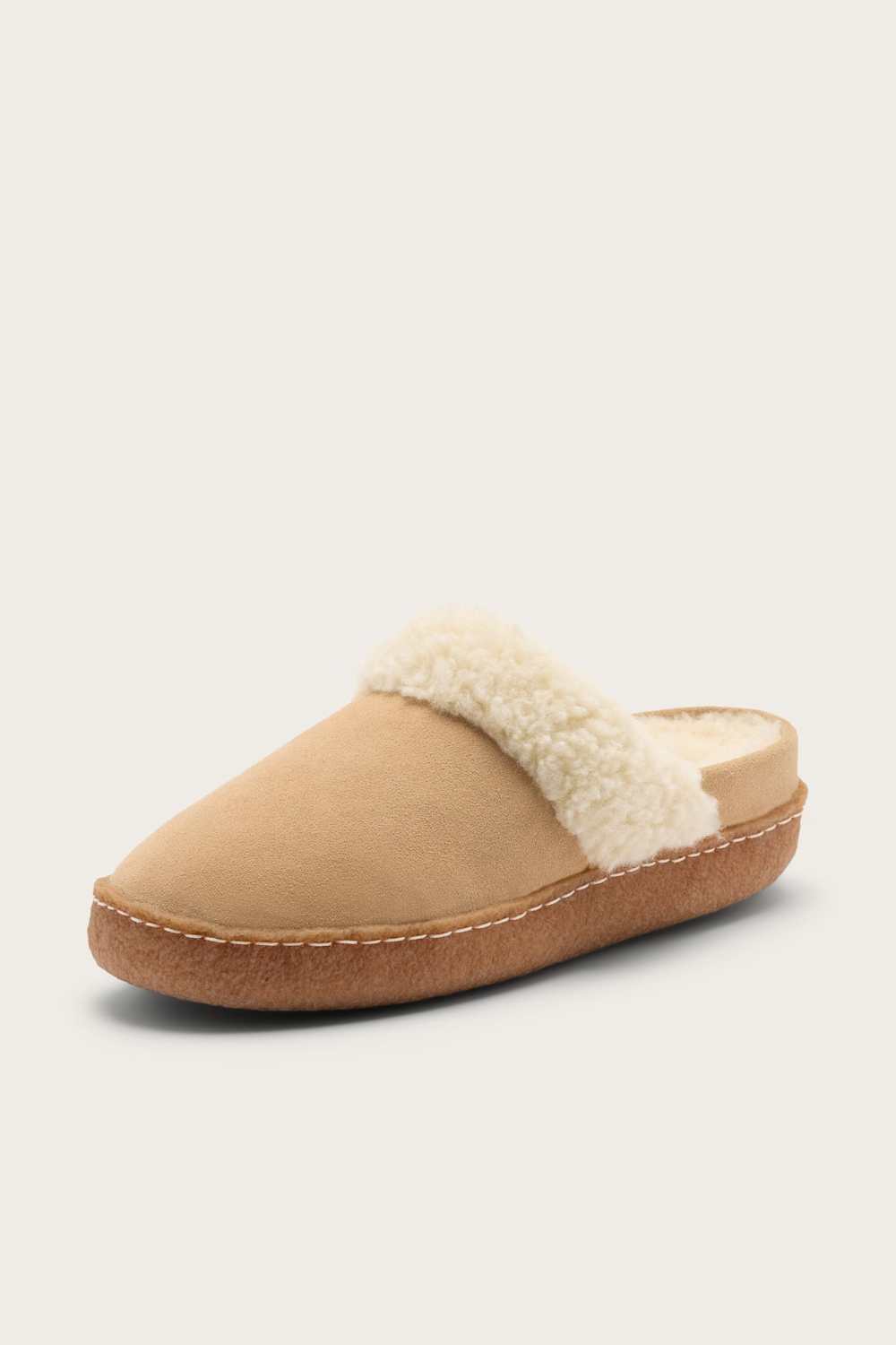 A single slip-on mule slipper in beige suede with a cream-colored faux shearling collar and a brown sole, shown against a light beige background.