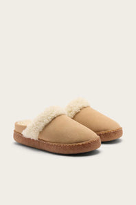 A pair of beige slip-on slippers with a soft cream faux-fur trim and a brown sole, shown against a light beige background.