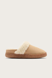 A single slip-on mule slipper in beige suede with a fluffy cream shearling collar and a brown cork-look sole, shown against a light gray background.