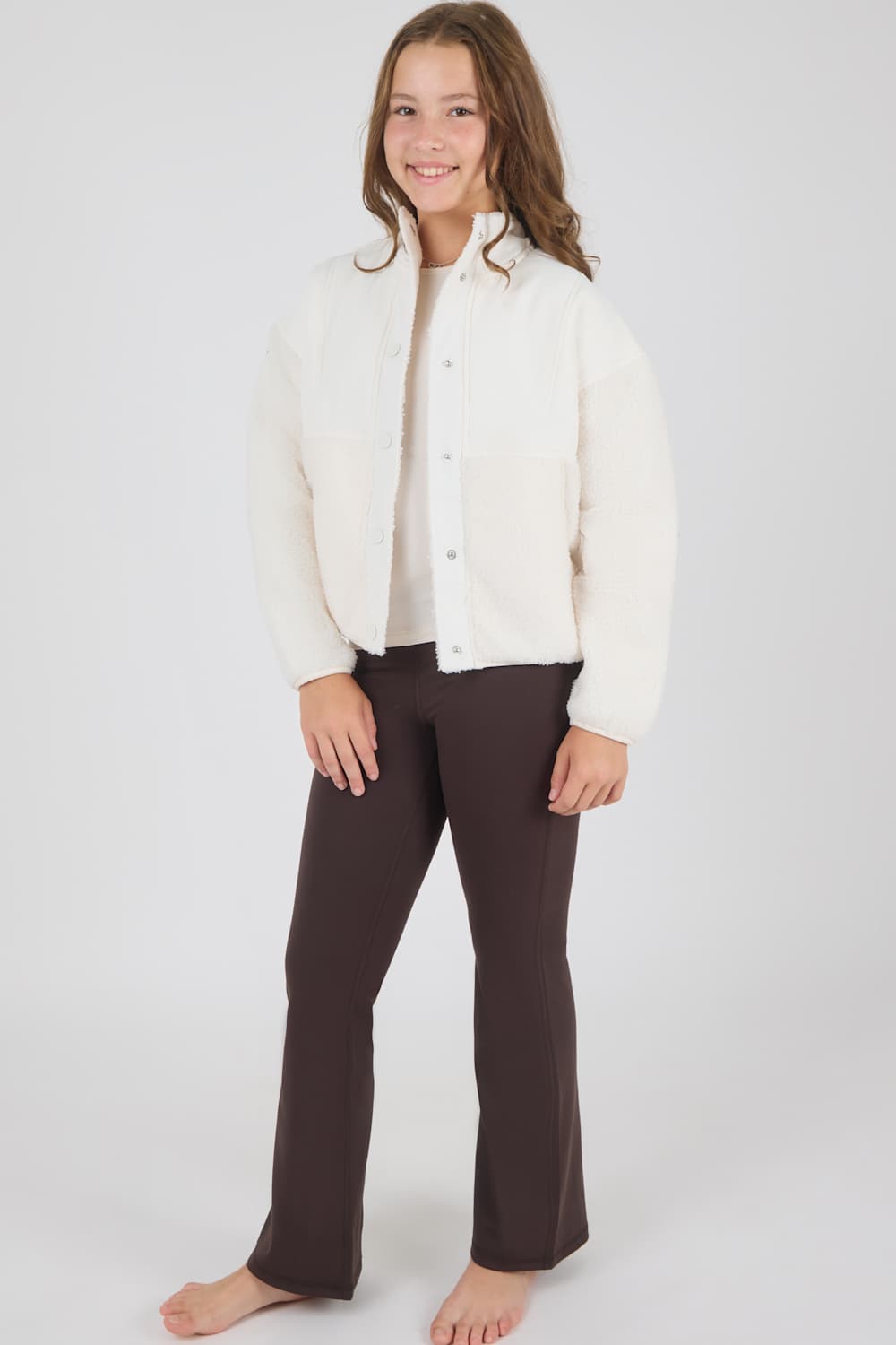 girl modeling a white jacket with matching brown flare leggings