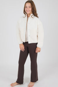 girl modeling a white jacket with matching brown flare leggings