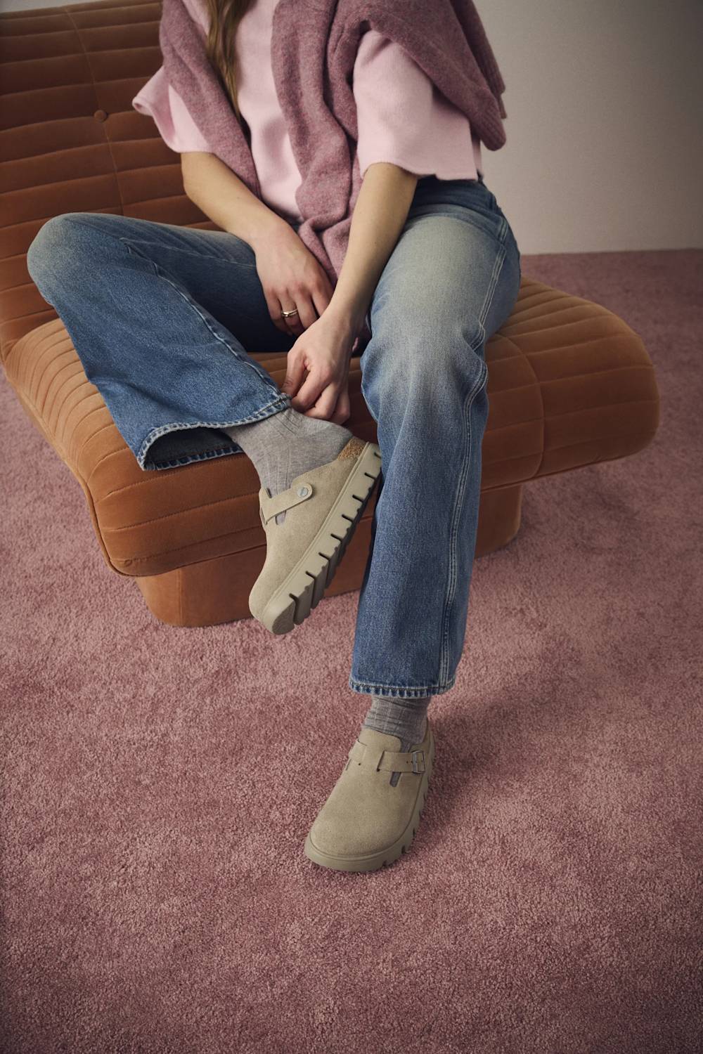 A pair of beige clogs with a strap closure and chunky soles