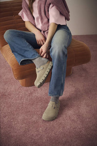 A pair of beige clogs with a strap closure and chunky soles