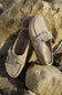 Pair of brown suede shoes with buckles on a rocky surface