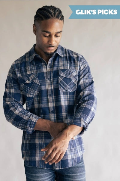 A man wearing a blue and beige plaid flannel with denim jeans standing against a grey background and a blue flag badge in the upper right corner that read GLIK'S PICKS