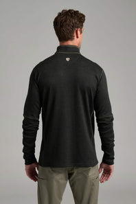A man viewed from behind wearing a dark charcoal gray long-sleeve quarter-zip pullover with a small shield logo on the upper back, paired with khaki pants, against a neutral gray studio background.