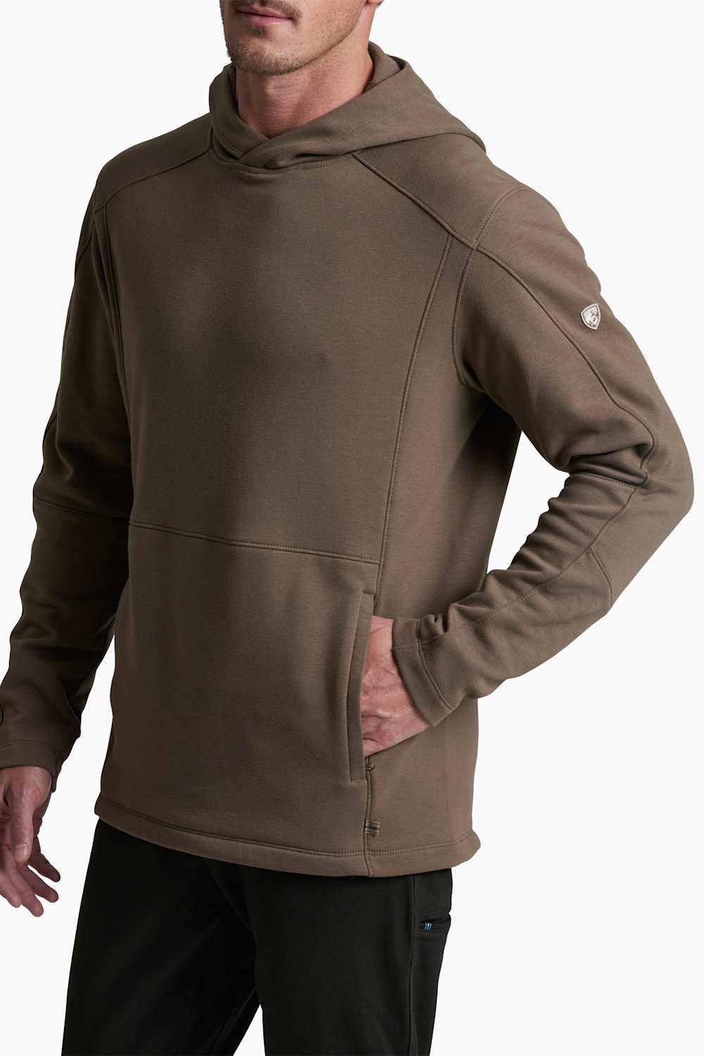 A man wearing a brown hooded sweatshirt with a kangaroo pocket and a zippered front, paired with black pants, shown against a plain white background.