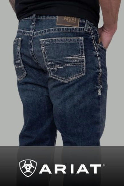 A promotional image of a person views from the back wearing dark wash jeans with light tan stitching and a branded ARIAT leather patch logo above the right back pocket. A black banner stretches along the bottom with ARIAT text and the branded shield logo