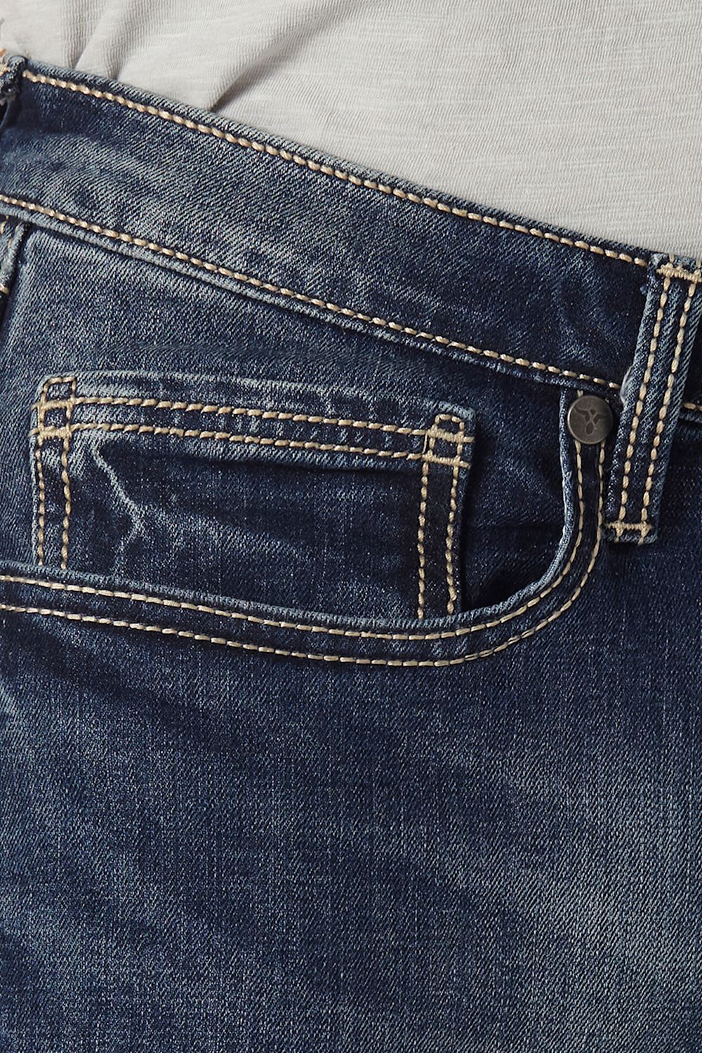 Close-up of dark blue denim jeans showing the back pocket with contrast tan stitching, a metal button, and a light gray top fabric at the waist.
