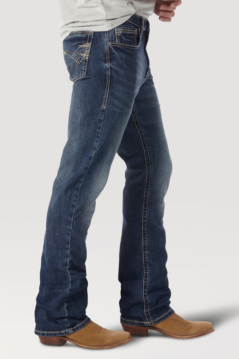A person wearing dark blue western flare jeans with decorative stitching on the back pocket, paired with tan cowboy boots, shown from the waist down against a light gray studio background.