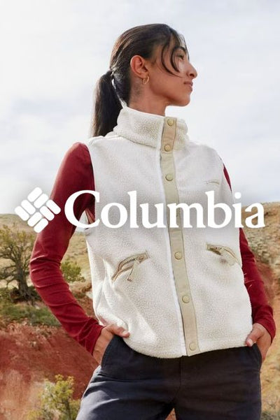 An image of a woman standing outdoors wearing a button up fleece best with a read long sleeve layered underneath. The Columbia logo sits in the middle overtop the image in white