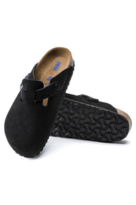 A pair of black clog-style mules with a suede-like upper and a contoured sole, shown on a clean white background.