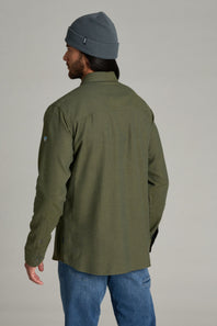 A man wearing an olive green long-sleeve button-up shirt and a gray beanie, shown from the back against a plain light gray studio background.