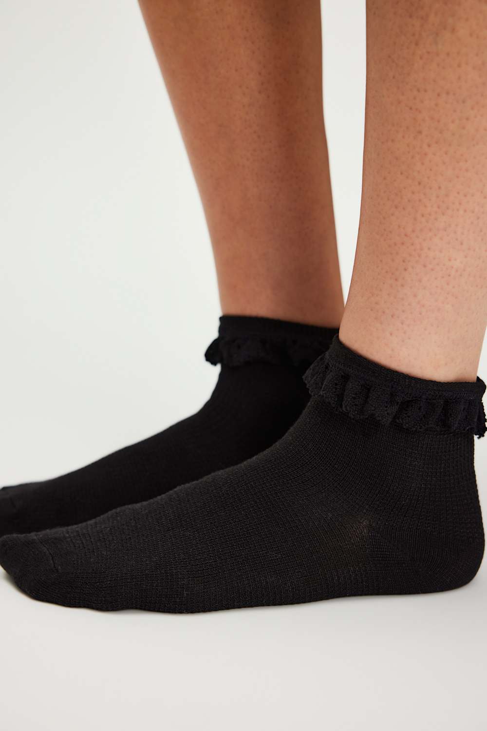Black ruffled socks worn by a person on a light gray background