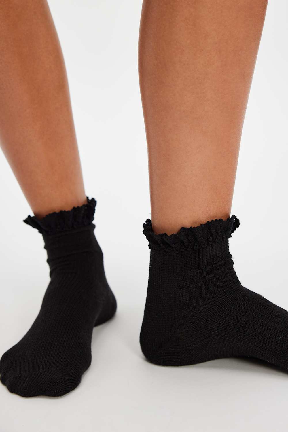 Black ruffled socks worn by a person on a white background