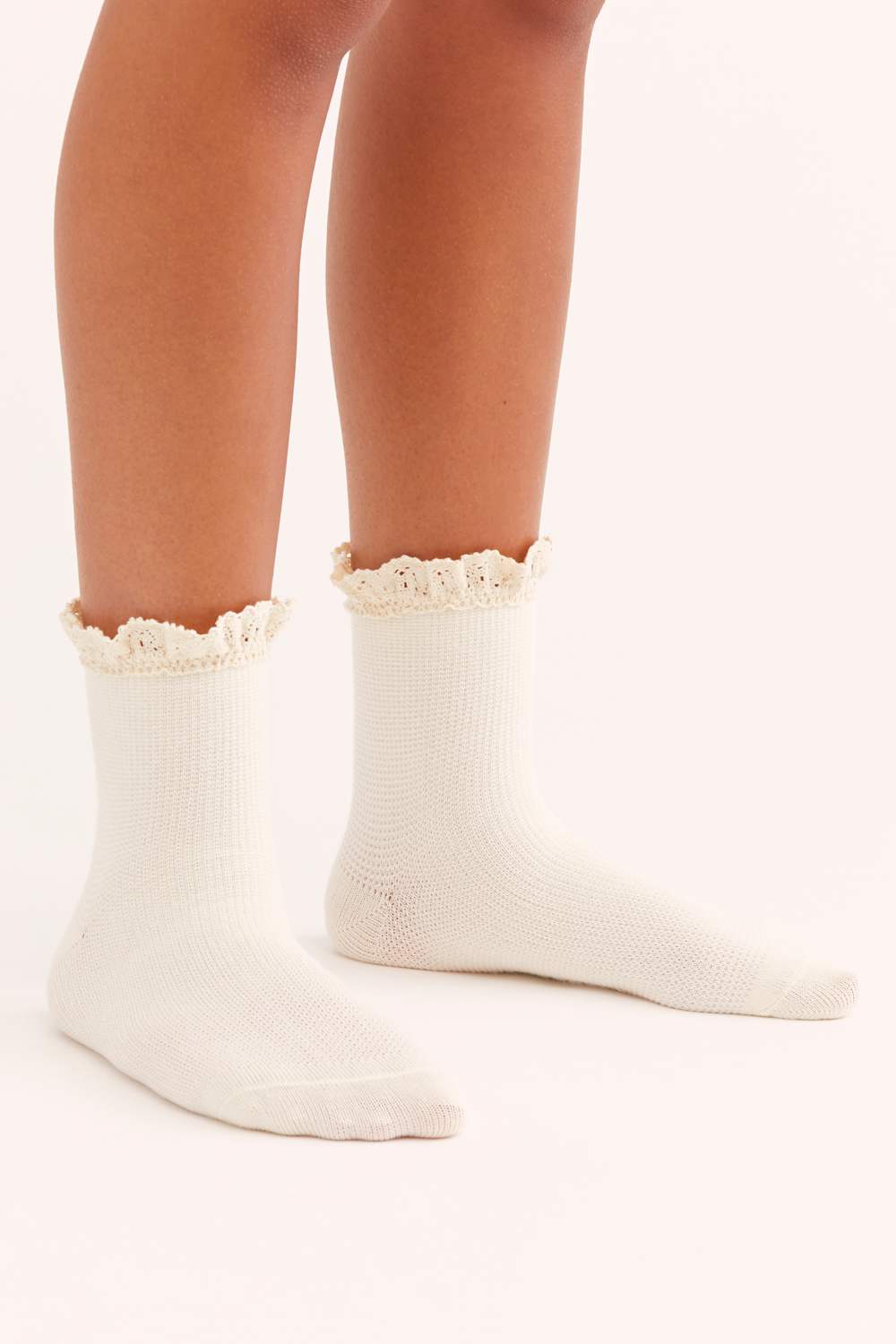 White socks with lace trim worn by a person on a white background