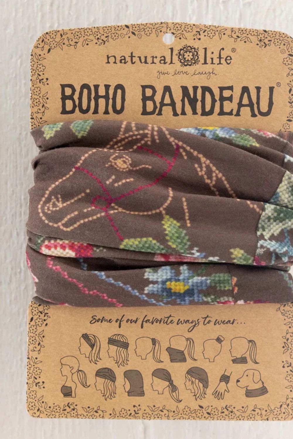 A brown fabric boho headband with a colorful horse and floral pattern, packaged on a brown kraft paper card labeled 'natural life BOHO BANDEAU'.