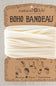 A cream-colored fabric headband wrapped in its original brown kraft paper packaging card, labeled 'natural life BOHO BANDEAU'.