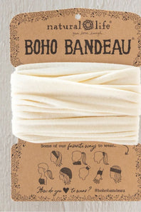 A cream-colored fabric headband wrapped in its original brown kraft paper packaging card, labeled 'natural life BOHO BANDEAU'.