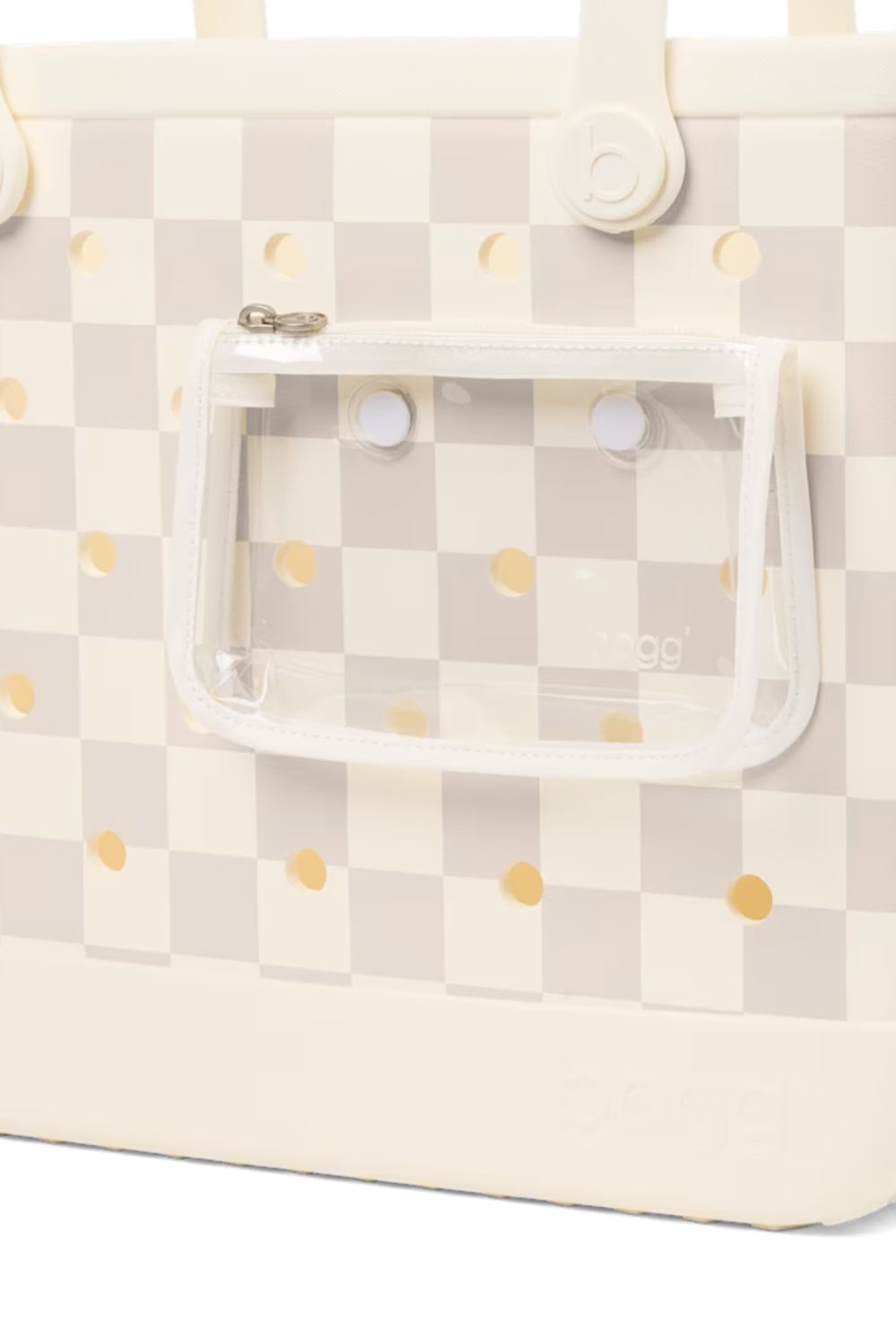 Close-up of a tote bag with a cream and light gray checkerboard pattern, small gold polka dots, and a clear zippered pouch attached on the front.